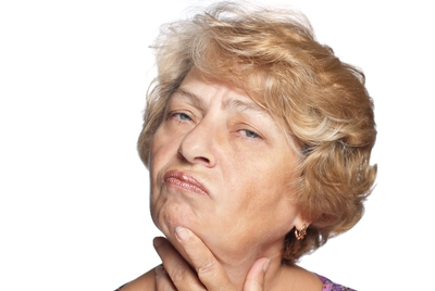 An image of the head of an older woman, thoughtfully stroking her chin.