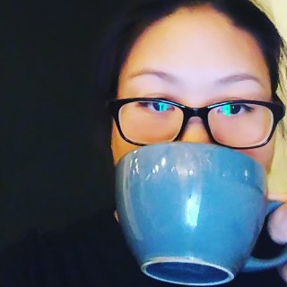 Maxie Bai Martin holds a blue mug in front of her face.