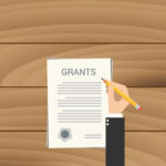 Person holding a pencil over a page titled “Grants.” (Copyright: binaryproject © 123RF.com)