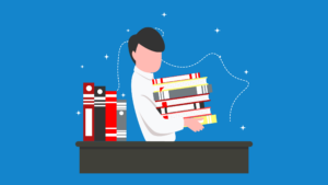 A person stands behind a desk holding a large stack of books, with more books on one side of the desk. (Copyright: nevesgraphic © 123RF.com)